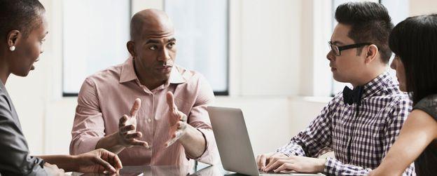 A seated person in a group setting explaining something